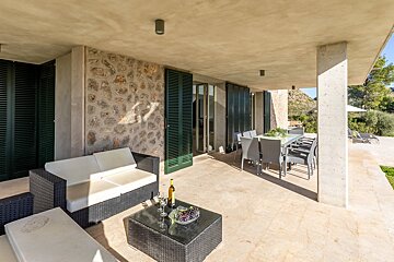 A patio with a couch and a table with a bottle of wine on it