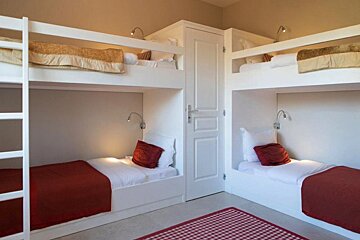 Four bunk beds in a room with a checkered rug