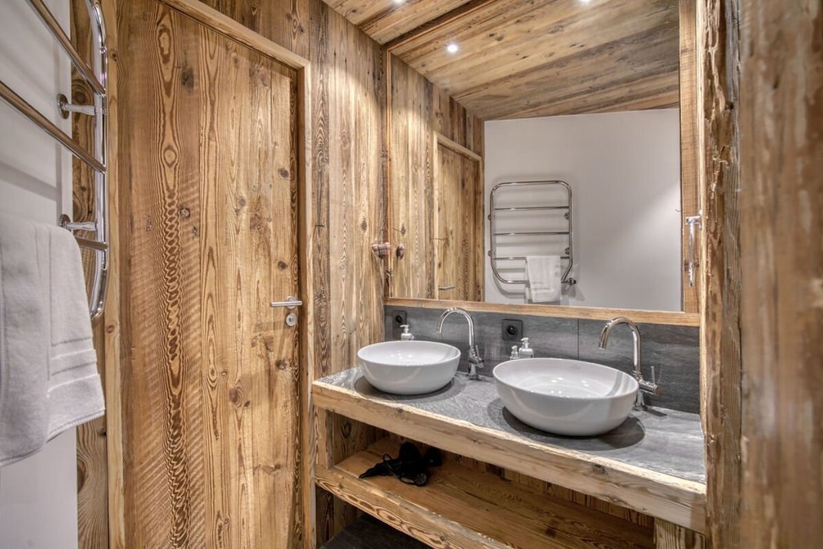 Rustic wooden bathroom featuring a double vanity with two white vessel sinks and a large mirror.