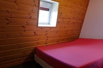 A small bedroom with a bed and a window