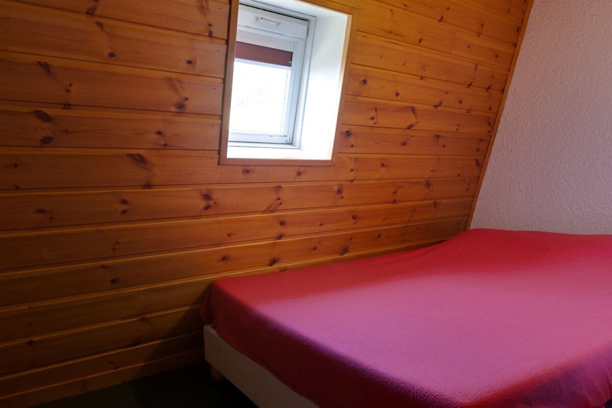 A small bedroom with a bed and a window