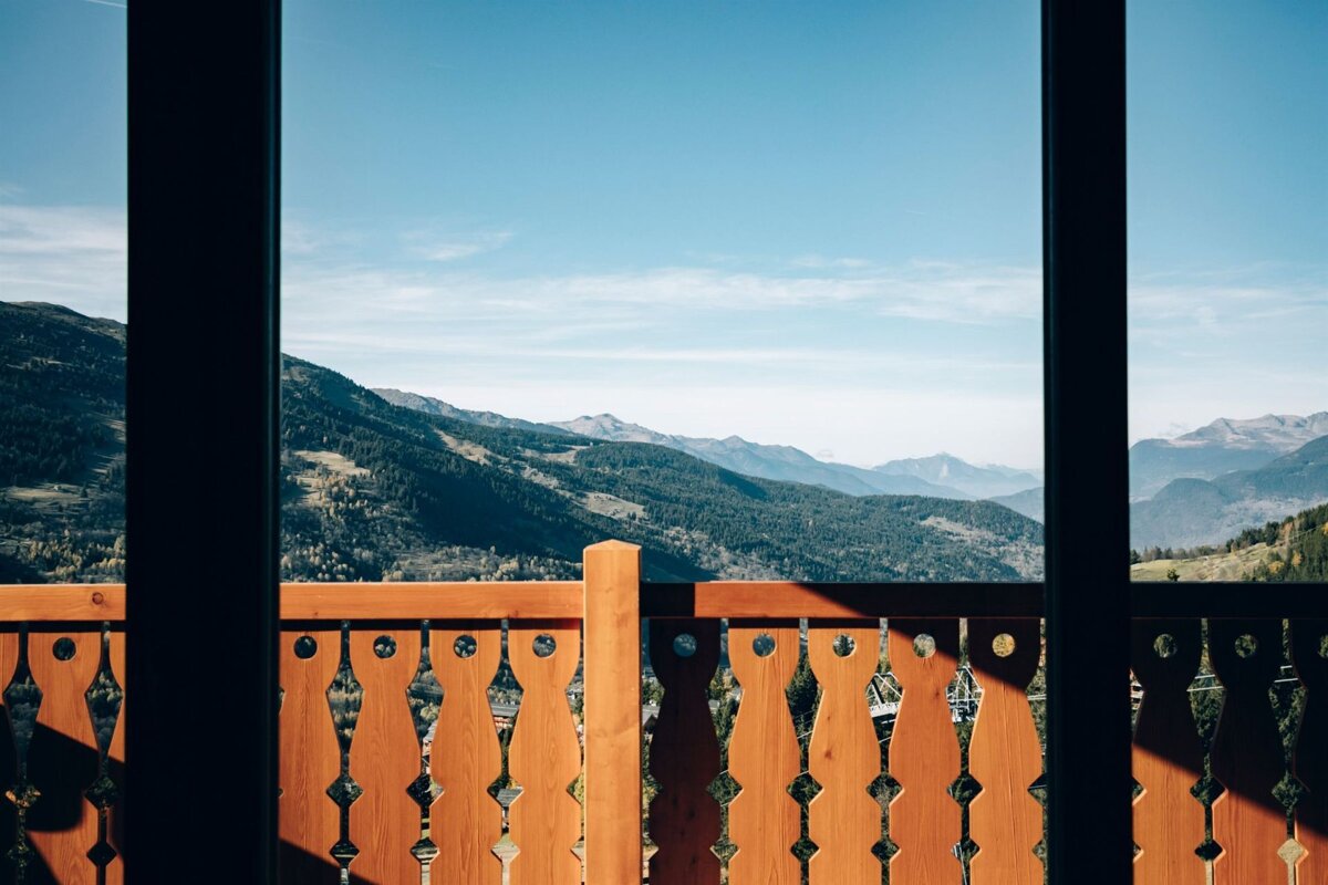 A view of the mountains from a balcony with a wooden railing