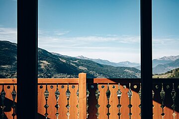 A view of the mountains from a balcony with a wooden railing