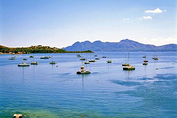 A large body of water filled with boats and mountains in the background