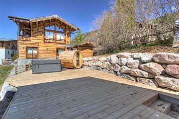A large wooden house with a hot tub in front of it