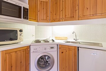 A kitchen with a washing machine and a microwave