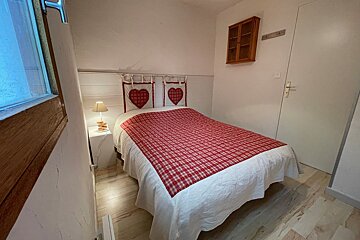 A bedroom with a bed and two hearts on the headboard