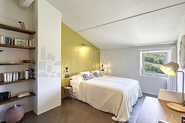 A bedroom with a bed and a bookshelf with a picture of a house on it