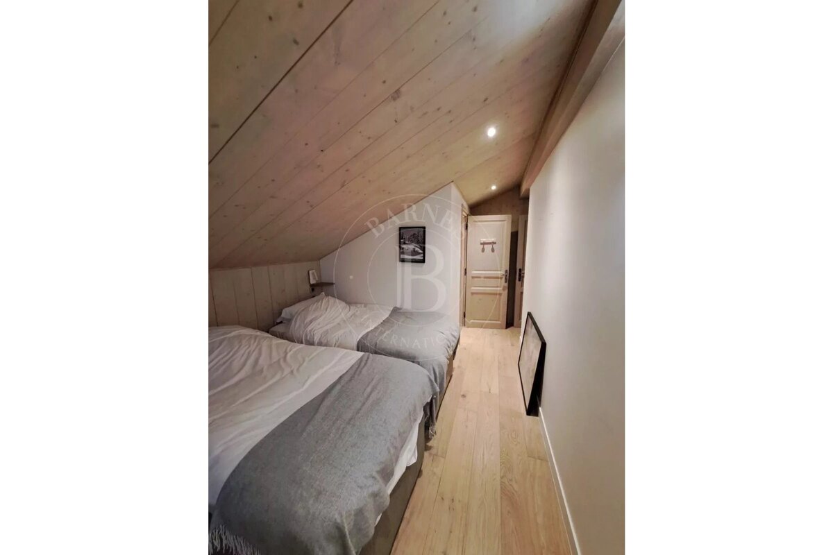 A bedroom with two beds and a picture on the wall with the letter b on it