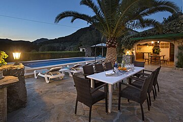 A patio with a table and chairs in front of a pool