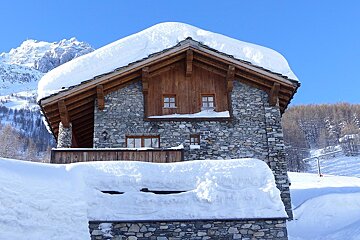 A snow covered stone building with a mountain in the background
