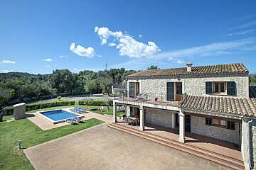 A large stone house with a large swimming pool in front of it