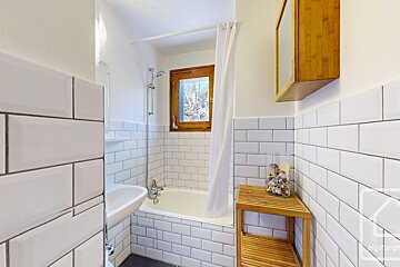 Cozy bathroom with white subway tiles, a bathtub/shower, sink, and wooden accents including a window frame, shelf, and medicine cabinet.