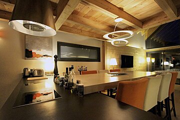 A kitchen with a large table and chairs and a bottle of vodka on the counter