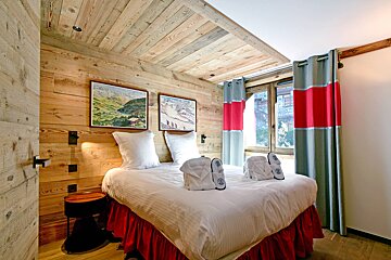 A bedroom with a wooden wall and a bed