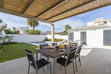 A patio with a table and chairs and a pool in the background