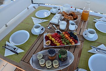 A table topped with plates and utensils with a plate of fruit on it