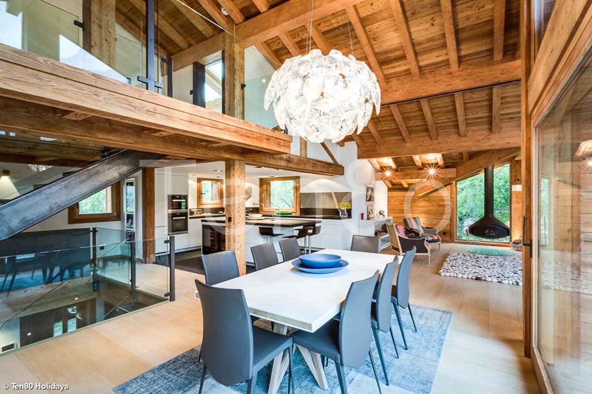 A dining room with a white table and chairs and a chandelier hanging from the ceiling