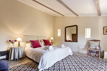 A bedroom with a large bed and a mirror