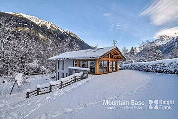 A snow covered cabin is owned by mountain base immobilier real estate