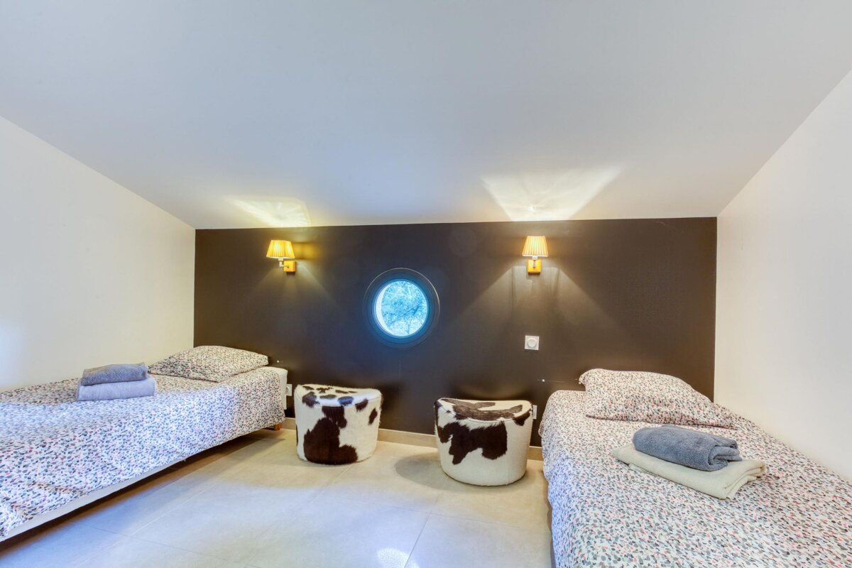 A bedroom with two beds and two cow print ottomans