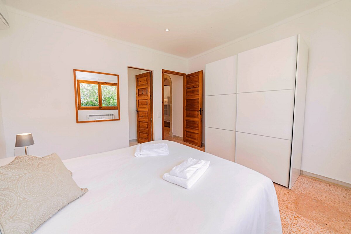 A bedroom with a white bed and a mirror