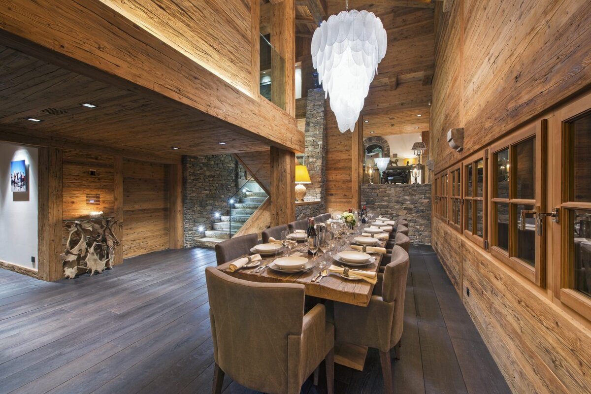 A wooden dining room with a long table and chairs