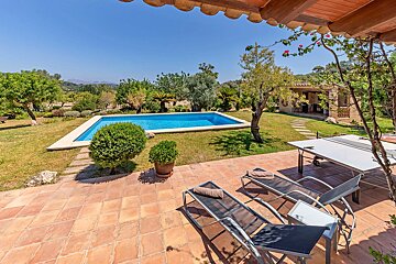 A patio with chairs and a table with a pool in the background