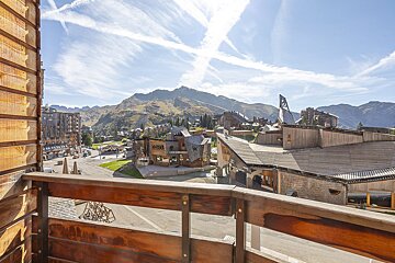 A balcony with a view of a ski resort and mountains