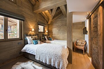 A bedroom with two twin beds and a chair