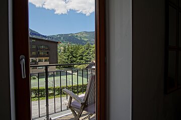 A balcony with a view of a tennis court and a building that says christal
