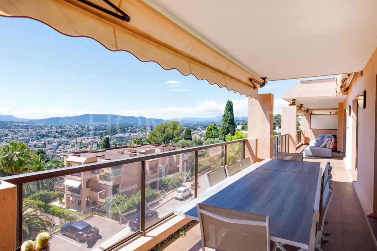 A balcony with a table and chairs and mountains in the background