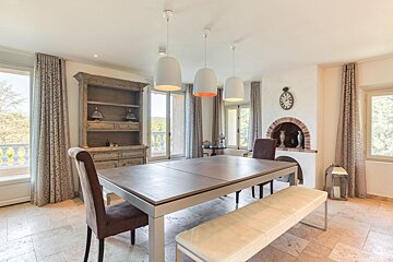 A dining room with a table and chairs and a clock on the wall