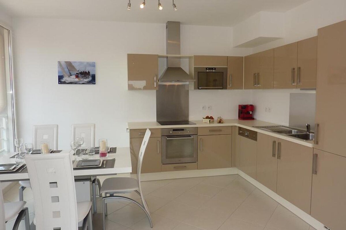 A kitchen with a picture of a sailboat on the wall above the stove