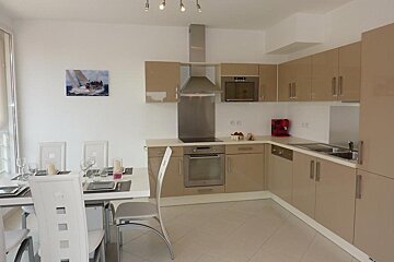 A kitchen with a picture of a sailboat on the wall above the stove