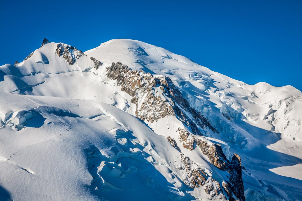 A snowy mountain with a blue sky in the background