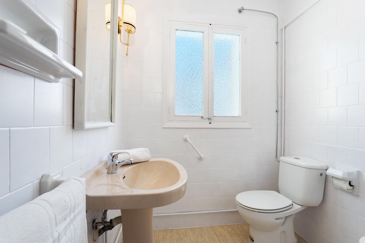 A bathroom with a sink and toilet and a window