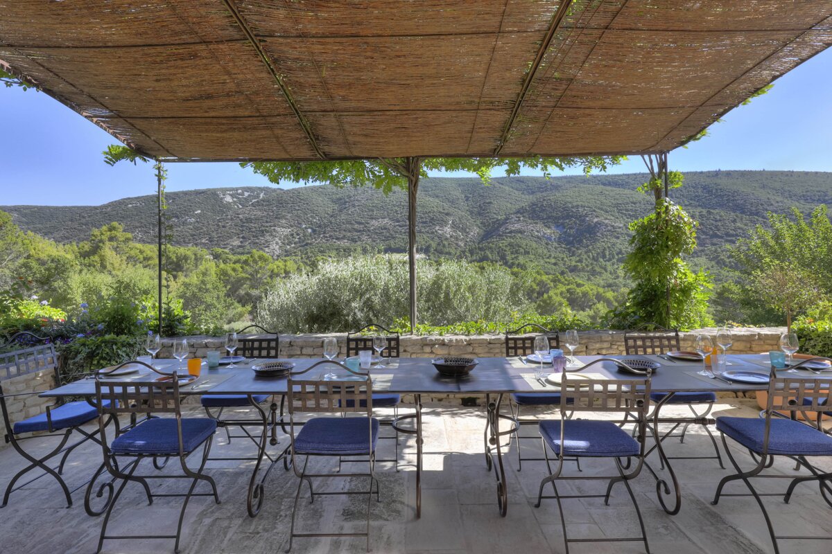 A table and chairs under a canopy with mountains in the background
