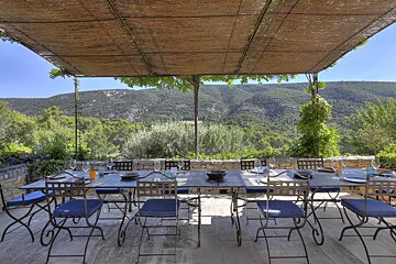 A table and chairs under a canopy with mountains in the background