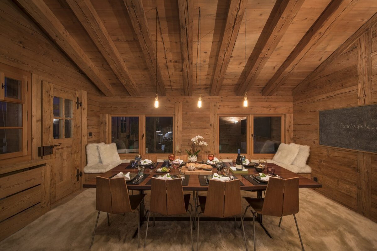 A wooden dining room with a table and chairs and a chalkboard that says bon appetit