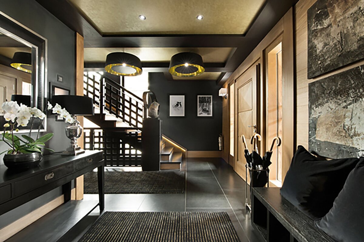 A hallway with a staircase and umbrellas on a bench