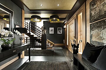 A hallway with a staircase and umbrellas on a bench