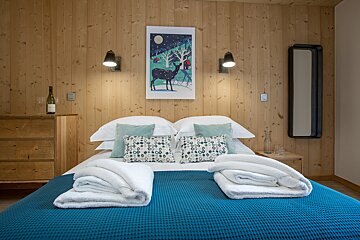 A bedroom with a painting of a deer on the wall above the bed