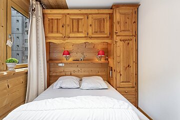 A small bedroom with a bed and wooden cabinets