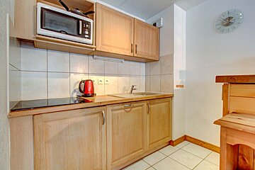 A kitchen with a microwave and a clock on the wall