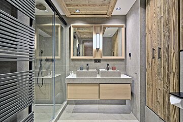 A bathroom with two sinks and a walk in shower