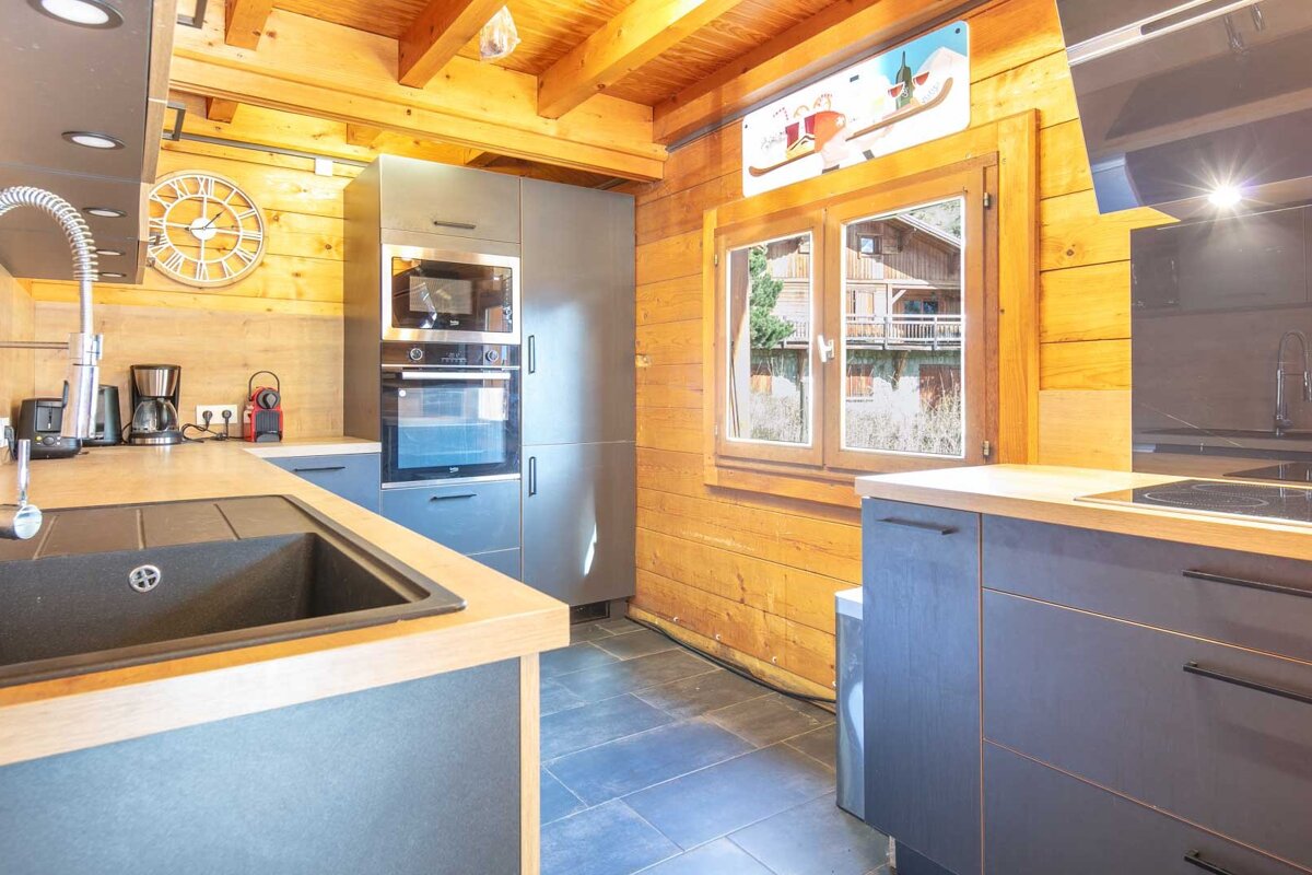 A kitchen with a clock on the wall above the sink