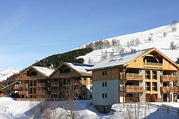 A row of houses with snow on the ground and mountains in the background