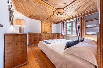 A bedroom with a wooden ceiling and a bed