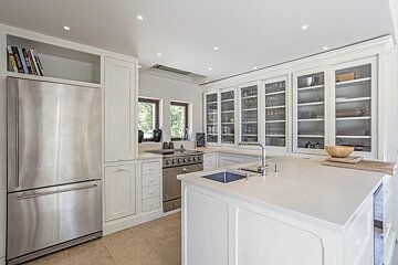 A kitchen with white cabinets and a stainless steel refrigerator